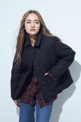 Campera acolchada de color negro con diseño capitoneado, cierre frontal con botones y cuello clásico.