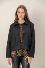 Chaqueta corta de paño en color negro, con cuello camisero, cierre frontal de botones y dos bolsillos frontales aplicados.