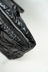 Cartera tipo shopper de color negro, con diseño acolchado y costuras cuadradas. Cuenta con doble asa larga para llevar al hombro y cierre superior.