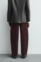 Pantalón de hombre color bordó oscuro, de corte ancho (wide fit), confeccionado en tejido de algodón con acabado flocada o efecto aterciopelado. Presenta cinco bolsillos y cierre frontal con cremallera y botón.