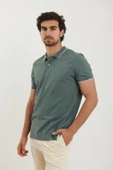 Chomba verde con cuello clásico y mangas cortas con ribete blanco.