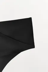 Tanga de tiro alto color negro con cintura ancha cruzada.