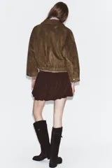 Falda corta de tiro alto con diseño abullonado y cierre lateral oculto.