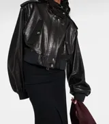 Campera bomber corta de cuero sintético negro, con cuello alto, cierre frontal y detalles de botones metálicos plateados en hombros y bolsillos frontales.