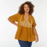 Blusa color mostaza de gasa de algodón con escote en V y bordado floral blanco en el frente.