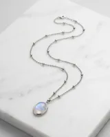 Collar de acero con cadena de eslabones finos con pequeñas esferas intercaladas y dije ovalado con piedra de la luna engarzada.