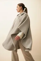 Poncho de lana fina sin teñir, con cuello camisero, cartera con broches a presión y bolsillo ojal. Diseño de estilo campestre con textura tejida.