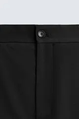 Pantalón de vestir regular fit color negro, confeccionado en tejido con mezcla de lana y elasticidad. Cuenta con cintura elástica, bolsillos frontales, bolsillos traseros de vivo con botón, y cierre frontal con cremallera y botón.