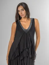 Vestido largo negro de seda con escote en V adornado con lentejuelas plateadas. Presenta un diseño de capas superpuestas con terminaciones deshilachadas que aportan volumen y movimiento. Es de corte sin mangas con breteles anchos y espalda elastizada.