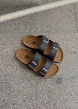 Sandalias de dos tiras marrones de ecocuero estilo Birkenstock, con hebillas metálicas ajustables y plantilla anatómica.