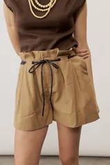 Short blanco de tiro alto, confeccionado en lino, con bolsillos laterales y cordón ajustable en la cintura.