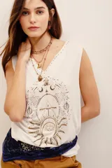 Musculosa de viscosa color blanco, sin mangas, con escote en V decorado con apliques y un gran estampado frontal de temática astrológica en tonos dorados y oscuros.