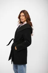 Tapado negro de corte cruzado con solapas amplias, capucha integrada y lazo ajustable en la cintura. Presenta cierre frontal con botones y bolsillos laterales.