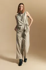 Pantalón ancho de tiro alto, color blanco roto con finas rayas verticales en color beige/marrón. Presenta un detalle de nudo o lazo en la cintura.