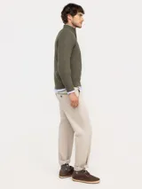 Sweater de punto acanalado en color azul marino, con cuello alto y cierre frontal parcial. Presenta mangas largas con puños acanalados y un pequeño logo bordado en rojo en el pecho.