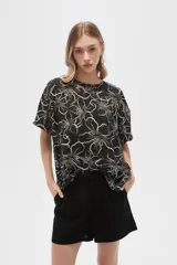 Blusa holgada de viscosa con estampado floral en tonos verde militar y blanco. Presenta cuello a la base, abertura frontal con botones y mangas cortas.