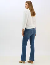 Camisa blanca de rayón con textura sutil, cuello con solapa, cierre frontal con botones y bolsillos simulados en el pecho. Presenta mangas 3/4 regulables con presilla y un diseño con nudo en el ruedo frontal.
