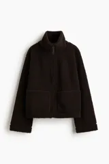 Campera de sherpa color marrón oscuro, con cuello elevado, cierre frontal y bolsillos de parche en los laterales.