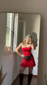 Vestido corto rojo sin mangas, confeccionado en jersey de lycra con delantera doble y corte ajustado. Incluye cinturón marrón con tachas.