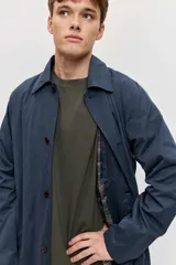 Abrigo largo azul marino de corte recto, con cuello camisero, cierre frontal con botones oscuros y bolsillos laterales ribeteados.