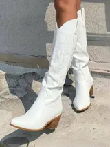 Botas texanas de caña alta color blanco, con diseño de costuras decorativas en el cuerpo de la bota, punta fina y taco cuadrado de madera.