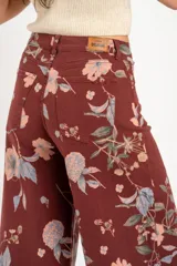 Jean de corte wide leg con tiro medio, confeccionado en algodón peinado. Presenta un diseño estampado con motivos florales sobre una base de color bordó.
