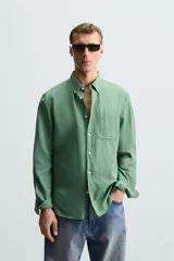 Camisa celeste a rayas verticales, de corte relaxed fit, confeccionada en lino y algodón. Tiene cuello abotonado, manga larga con puños abotonados, bolsillo de parche en el pecho y cierre frontal con botones.