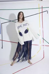 Sweater tejido a mano en lana merino color crudo, con bordado de uvas y la frase "Wine Not?". Tiene cuello redondo, mangas largas y corte holgado.