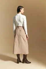 Falda midi de pana color marrón, con tiro alto, abotonadura frontal completa y bolsillos aplicados en el frente.