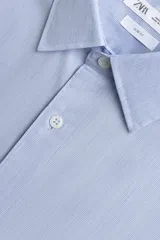 Camisa slim fit de algodón color celeste, con cuello italiano y manga larga con puños abotonados. Cierre frontal de botonadura.