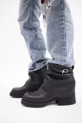 Botin de cuero vacuno color marrón con diseño de caña arrugada, punta redondeada y suela de plataforma negra con taco cuadrado.