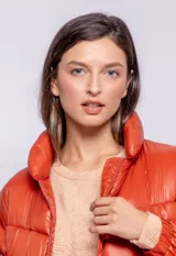 Campera puffer de diseño ochentoso con mangas removibles que permiten convertirla en chaleco. Presenta cuello alto, cierre frontal y cordón ajustable en la cintura.