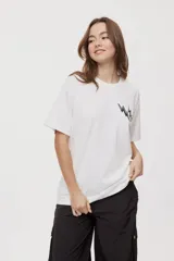 Remera de manga corta con calce oversized y cuello redondo, color gris oscuro, con pequeño gráfico de rayos naranjas en el frente.