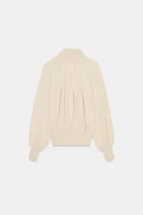 Blusa marrón de punto fluido, con cuello subido abotonado en un lateral y mangas largas con puños ajustados. Presenta un diseño fruncido en la parte frontal que aporta volumen.
