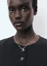 Chaleco sastre de corte recto y diseño sin mangas, con cuello redondo, tirantes anchos y cierre frontal mediante botones a tono.