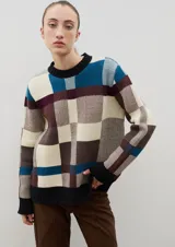 Sweater de punto con diseño jacquard a cuadros en tonos azul, marrón, crema y negro. Presenta cuello redondo, puños y ruedo acanalados, con un corte holgado y cómodo.