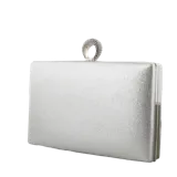 Cartera de fiesta tipo clutch rígida en color plateado con acabado brillante. Presenta un cierre superior con un original detalle de anillo decorado con cristales. Incluye una cadena metálica extraíble para llevar al hombro.