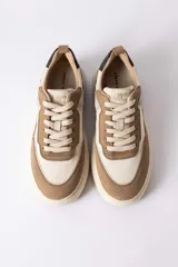 Championes urbanos de diseño moderno, combinando paneles de cuero texturizado en tono tostado y cuero liso en color crema. Presenta una suela de plataforma robusta en tono crema con un detalle en bloque tostado en el talón y un contrafuerte oscuro.