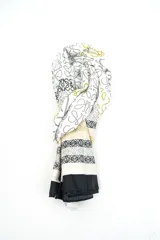 Pañuelo blanco de seda con estampado de monogramas en tonos negros, grises y mostaza, y detalles de franjas y bordes negros.