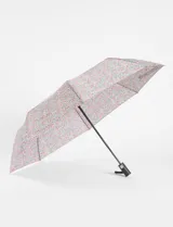 Paraguas plegable con sistema de apertura automática, estampado con un diseño de flores pequeñas en tonos rosados, azules y verdes sobre fondo claro. Cuenta con mango ergonómico negro y estructura resistente.