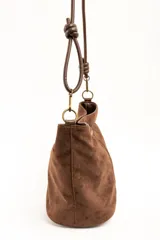 Cartera tipo bandolera de gamuza sintética color marrón, con asa larga decorada con nudos y detalles de herrajes metálicos dorados.