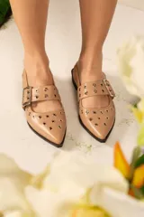 Zapato color beige con punta fina, tira sobre el empeine con hebilla metálica y detalle de ojales metálicos.