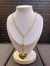 Collar dorado de cadena eslabonada con dije colgante en forma de corazón texturizado y diseño tipo corbatero.