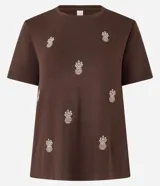 Blusa marrón de mangas cortas, confeccionada en viscosa, con cuello redondo y bordados de piñas en la parte delantera.