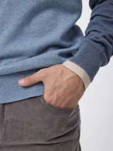 Sweater de tejido de punto en color azul, con cuello alto y cierre frontal parcial. Presenta mangas largas con puños acanalados y un pequeño detalle bordado en el pecho.