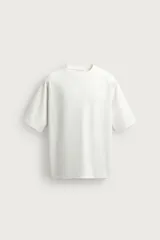 Camiseta relaxed fit color blanco crudo, confeccionada en tejido interlock de algodón, con cuello redondo y manga corta.