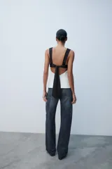 Top de escote cuadrado y tirantes anchos, con diseño bicolor en negro en la parte superior y blanco en el cuerpo, corte ligeramente acampanado y espalda descubierta con lazada.