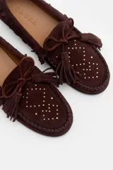 Mocasín de gamuza color bordó con detalle de flecos, cordones y tachas metálicas en la parte superior.