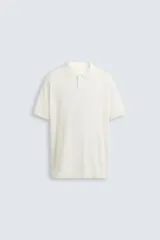 Polo de punto canalé color rosado, de corte regular fit, con cuello solapa y cierre frontal de botonadura. Manga corta y acabados en rib.