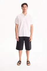 Bermuda de jean de algodón de estilo skater oversize en color negro, con diseño clásico de bolsillos y trabillas para cinto.